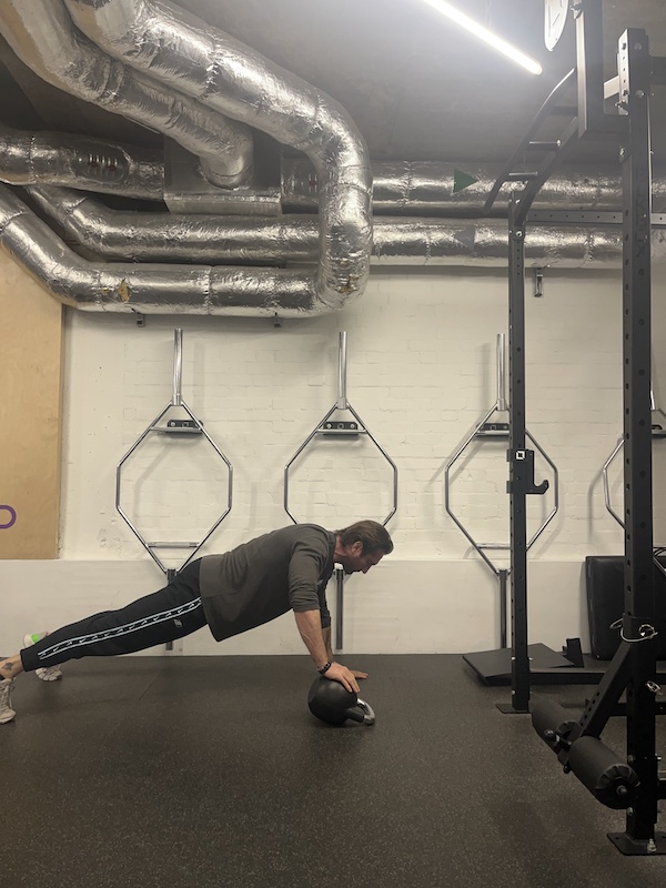 man performing kettlebell offset push-up in the gym