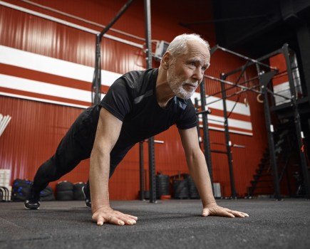 man in sixties performing push-up in gym