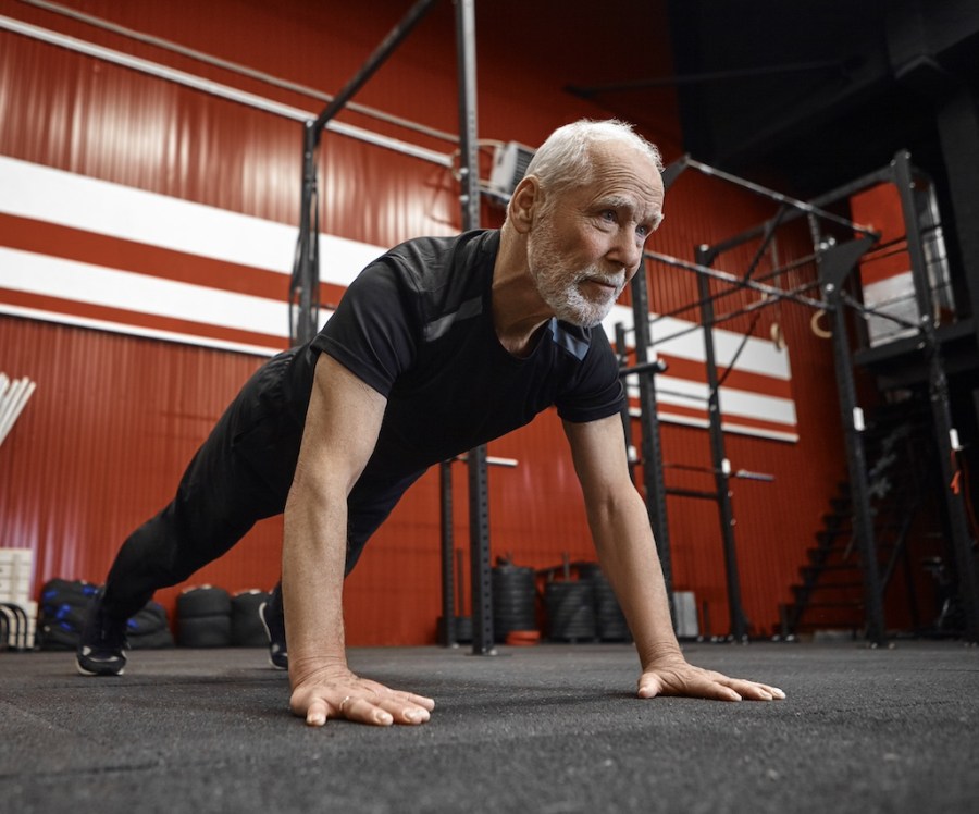 man in sixties performing push-up in gym