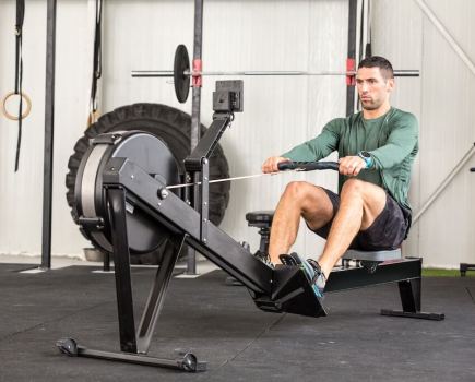 man in long sleeved green top working out on rowing machine