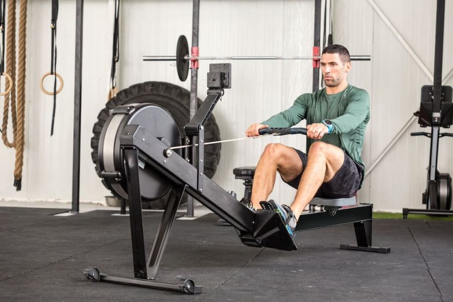 man in long sleeved green top working out on rowing machine