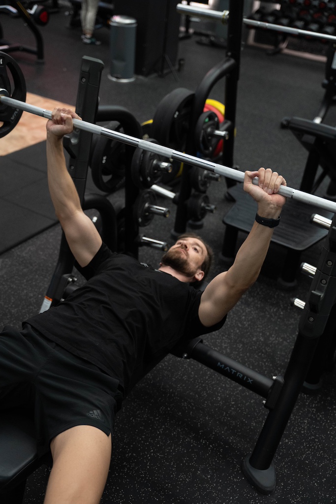 PT demonstrating how to perform a barbell bench press in a workout routine for beginners