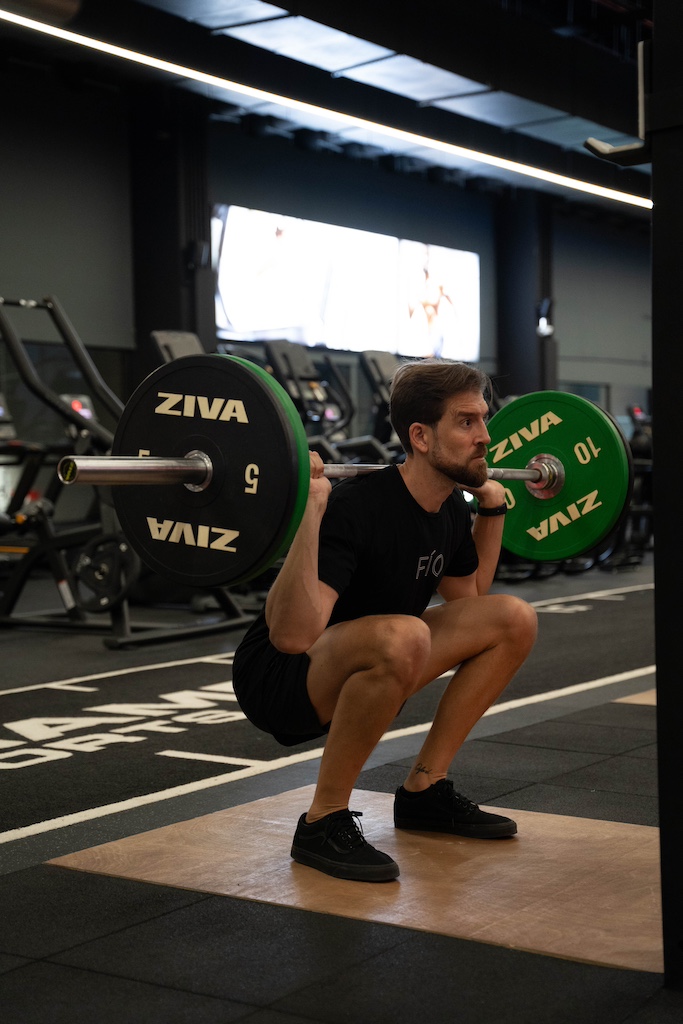 PT demonstrating how to perform a barbell back squat
