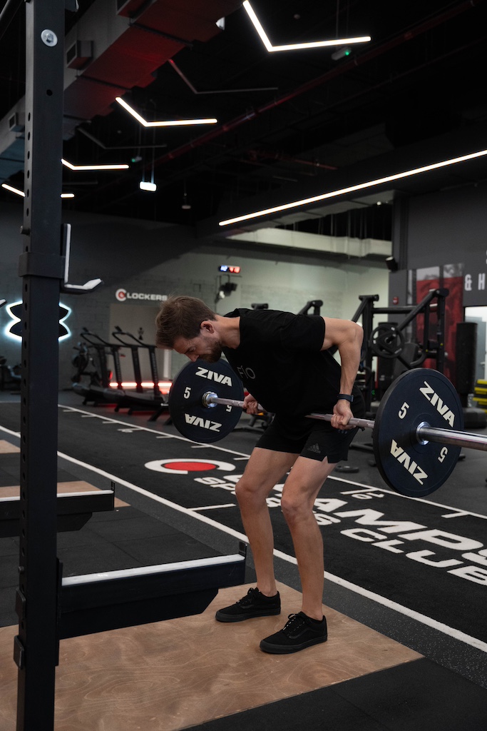 PT demonstrating how to perform a bent-over barbell row in a workout routine for beginners