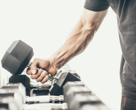Close-up of a man lifting a dumbbell off a rack