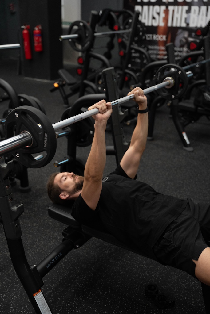 PT demonstrating how to perform a close-grip bench press in a workout routine for beginners