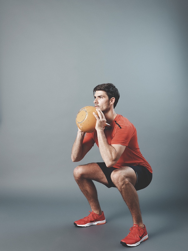 man in fitness kit demonstrating how to do a goblet squat as part of a beginners kettlebell workout