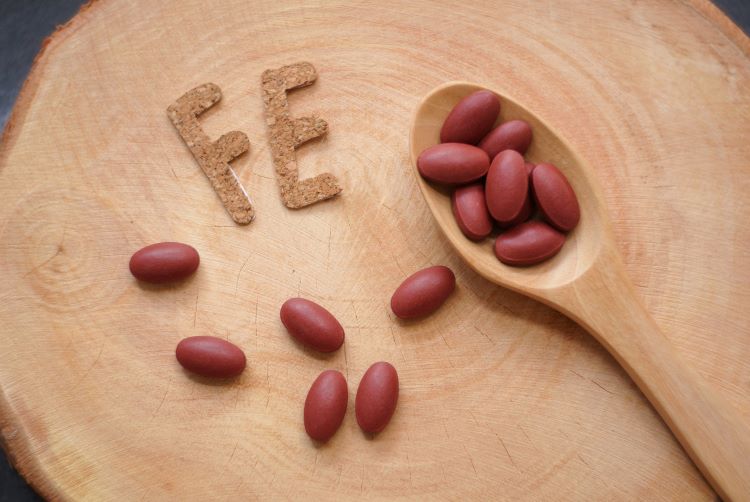 Wooden spoon and iron supplement tablets with the letters 'FE'