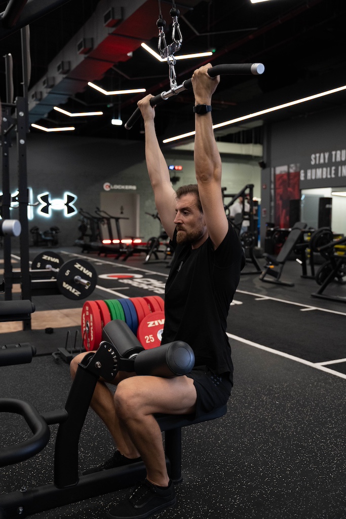PT demonstrating how to perform a lat pulldown with narrow grip in a workout routine for beginners