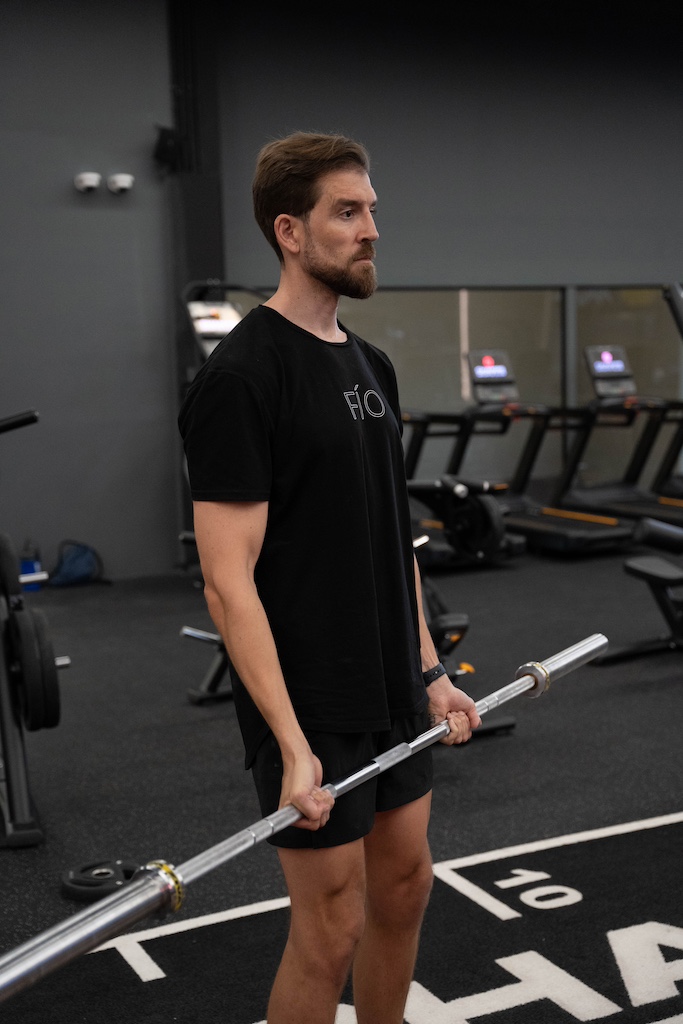 PT demonstrating how to perform a barbell curl in a workout routine for beginners