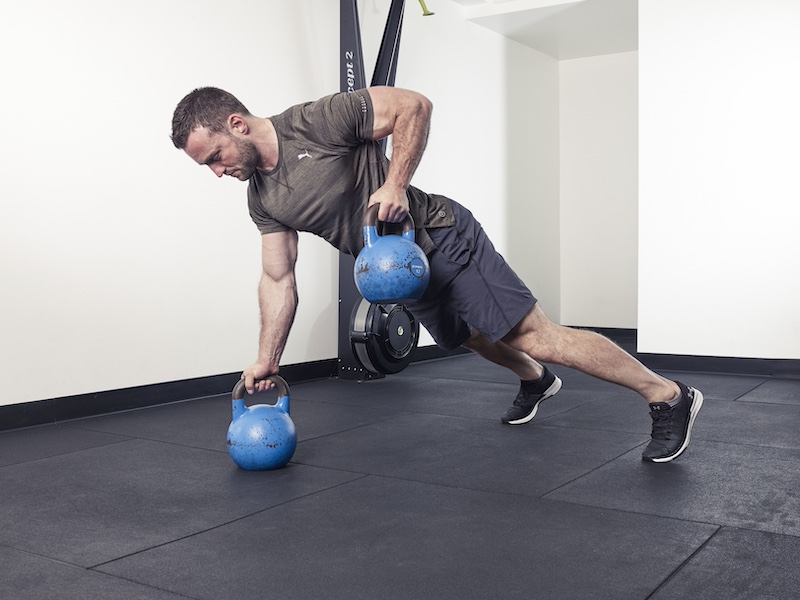 fitness model demonstrating how to perform a kettlebell renegade row