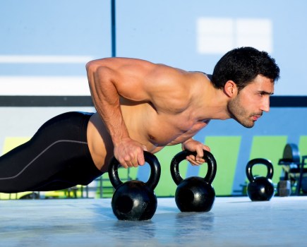man in gym performing kettlebell push-up