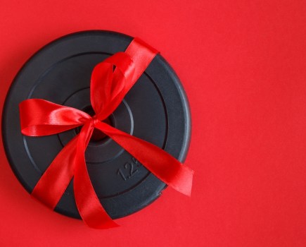 Weight plate wrapped in red ribbon as part of Men's Fitness' New Year Gift Guide