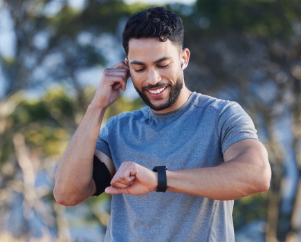 man looking at sports watch with headphones in