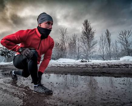 man in running kit crouched down on a cold wintery day