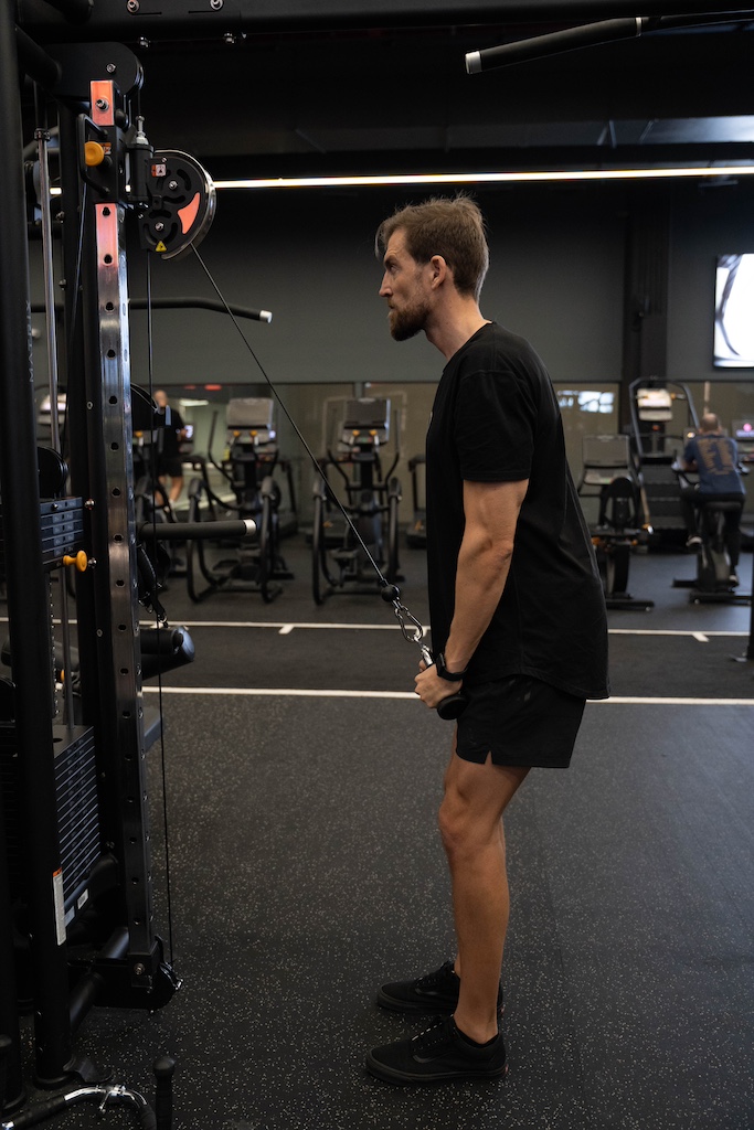 PT demonstrating how to perform a triceps pushdown