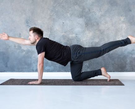 Man performing a bird-dog yoga pose