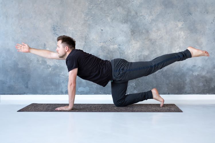 Man performing a bird-dog yoga pose