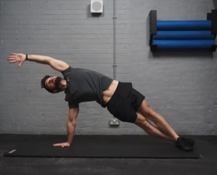 Man performing a high side plank with reach