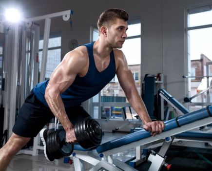 Man in a gym performing supported dumbbell row