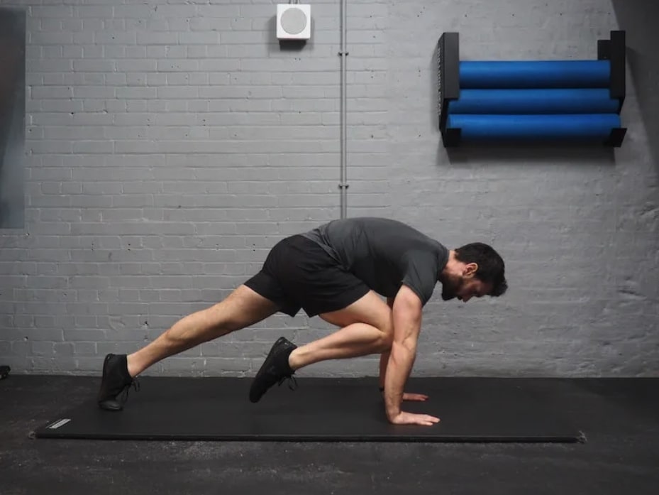 man performing high plank knee to elbow as part of one of the best core workouts for men