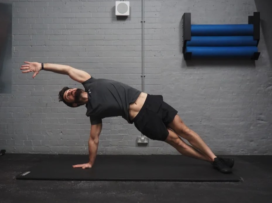 man performing high side plank with reach 