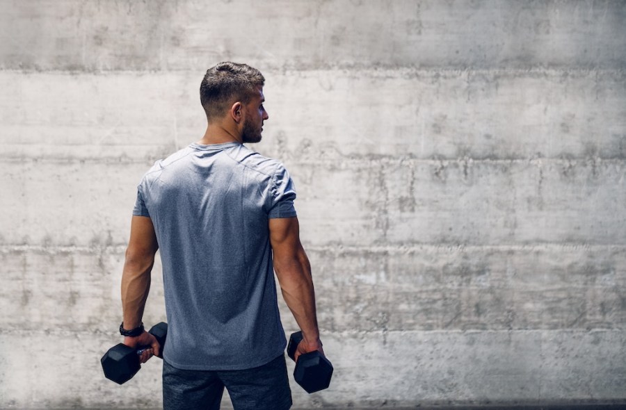man with back to camera holding pair of dumbbells