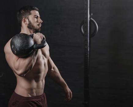 muscular man holding kettlebell on his shoulder