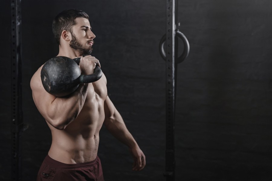 muscular man holding kettlebell on his shoulder