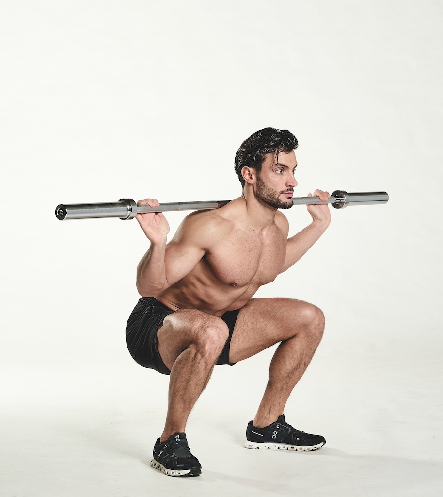 Man performing barbell squat as part of the busy man's training plan