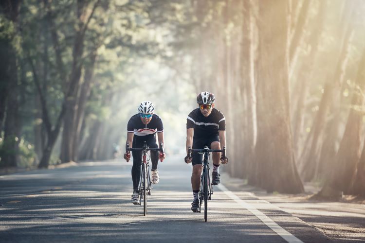 Two men cycling on forest road