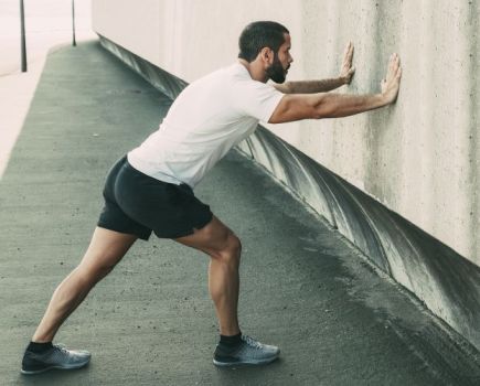 Runner stretching against a wall