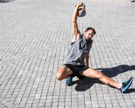 Man performing a Turkish get-up outdoors with a kettlebell