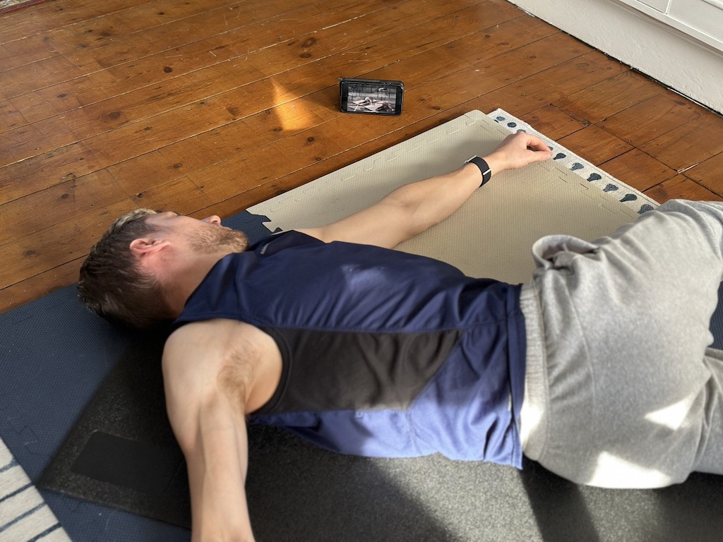 man performs mobility stretch on living room floor