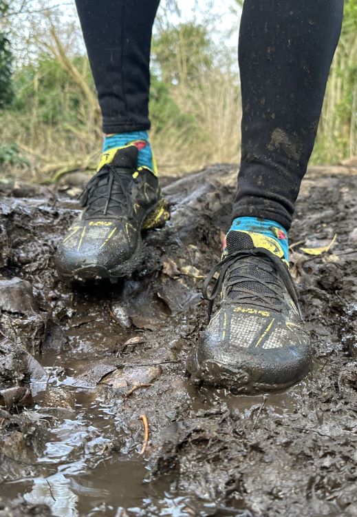 Close-up of a runner's shoes in mud