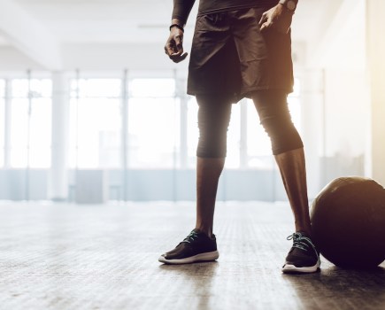 Athletic man standing in the gym beside a medicine ball. Close up of the lower half of a man working out in gym