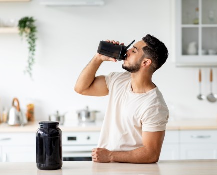 man drinking one of the best protein powders in kitchen