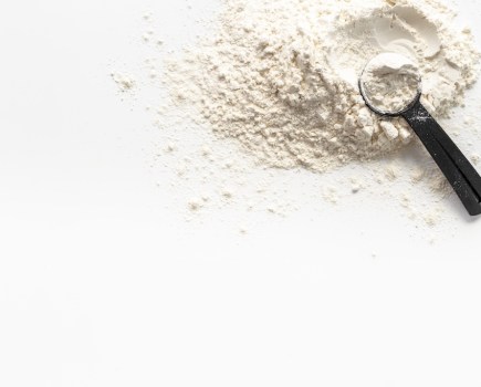 white protein powder with black scoop to show how much protein you should have with each meal