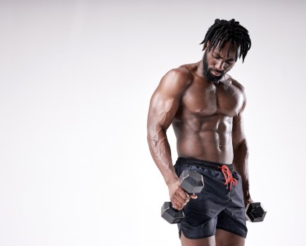 portrait of masculine young afro american man holding dumbbell isolated on white background. Naked Torso of young black man is perfect, doing cross fit workout, training, bodybuilding concept
