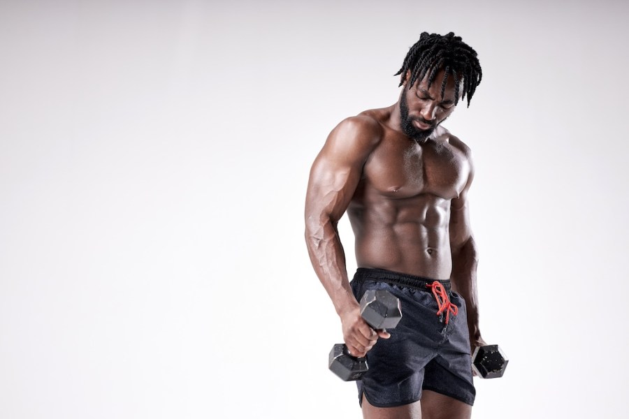 portrait of masculine young afro american man holding dumbbell isolated on white background. Naked Torso of young black man is perfect, doing cross fit workout, training, bodybuilding concept