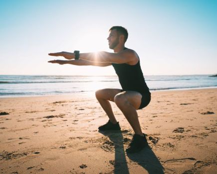 Man on a beach performing a bodyweight squat