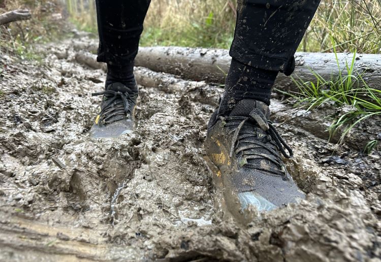 Off-road shoes sinking in a muddy trail