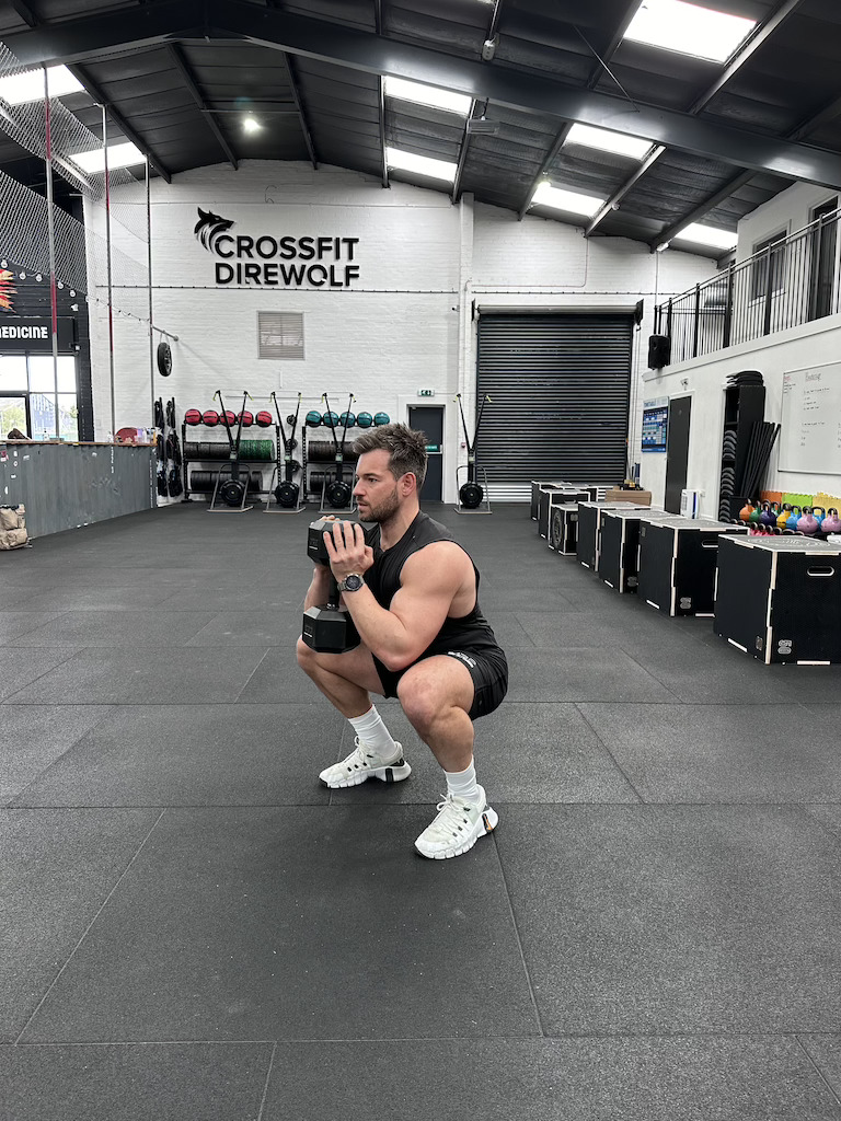 man performing dumbbell goblet squat as part of a dumbbell-only leg workout