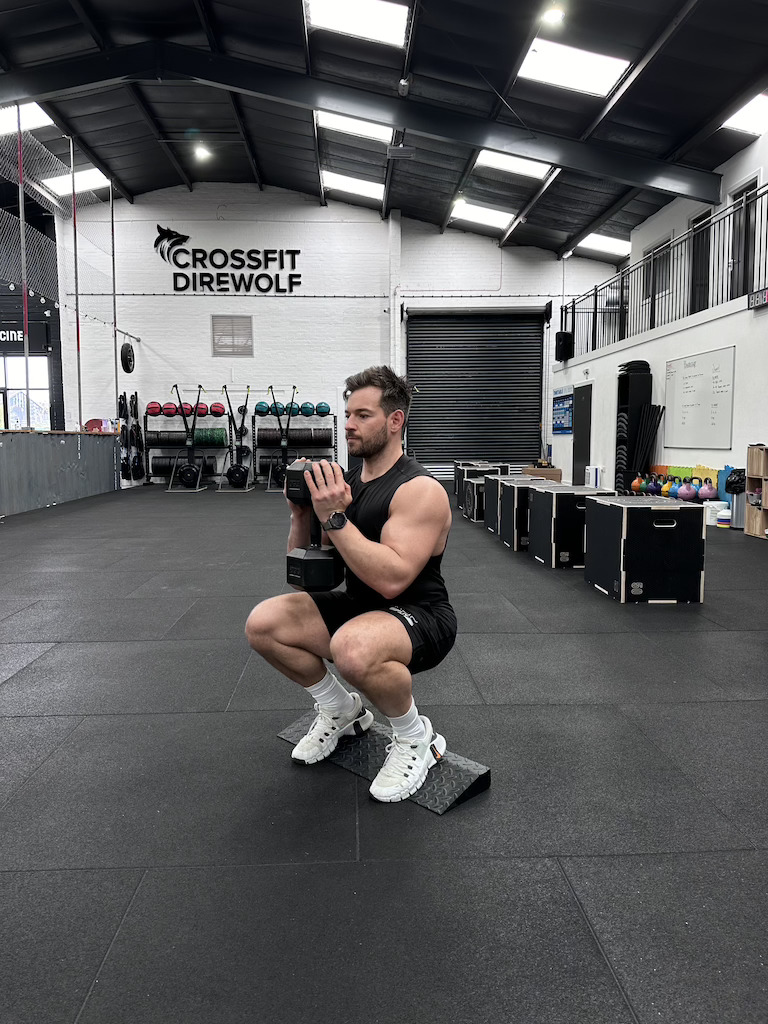 The Movement Blueprint founder Harvey Lawton performing a dumbbell goblet cyclist squat as part of a dumbbell-only leg workout 