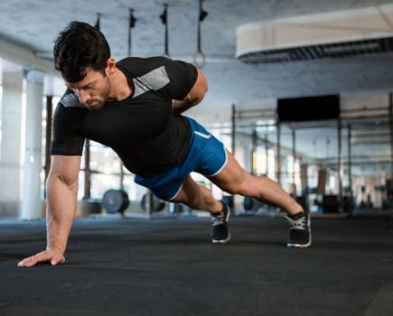 Man in a gym doing one-handed press-ups