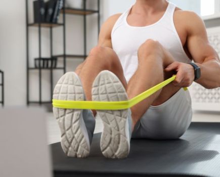 Close-up of a man's lower torso, exercising with resistance bands