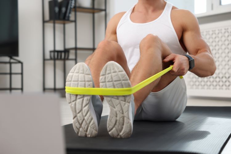 Close-up of a man's lower torso, exercising with resistance bands