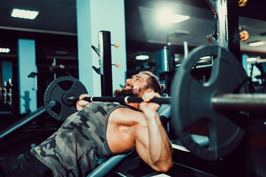 man in vest doing incline bench press in the gym to show time under tension