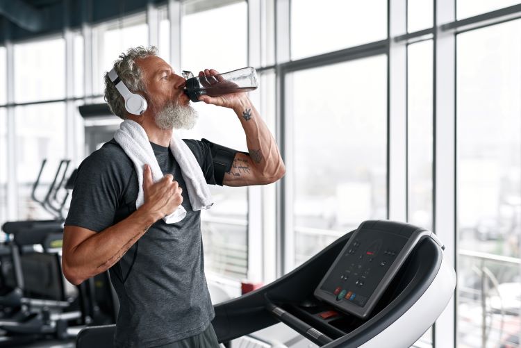 Middle-aged man in a gym drinking a sports drink