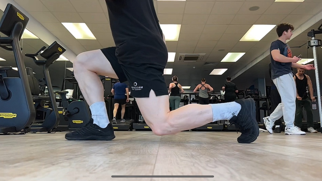 Man performing jumping lunge in the gym